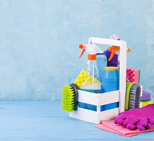 Cleaning caddy with spray bottles, brushes, and gloves ready for a home cleaning